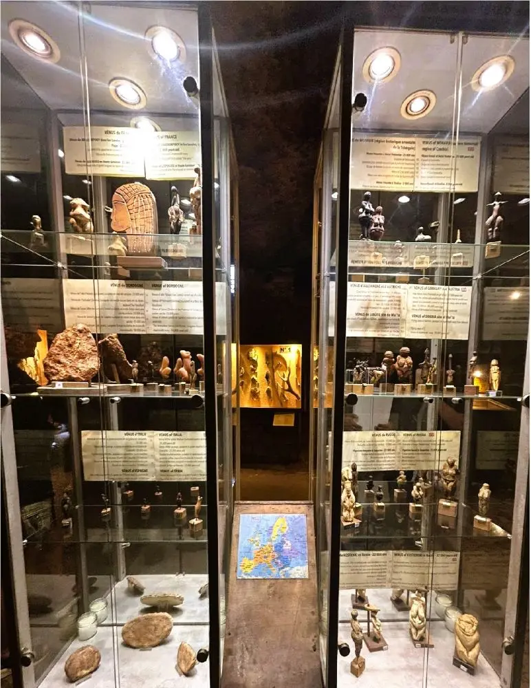 Vitrinas iluminadas con réplicas de Venus paleolíticas en el refugio prehistórico del castillo troglodita Maison Forte de Reignac.