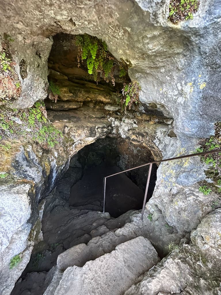 Escaleras de piedra descendiendo hacia el interior oscuro del castillo troglodita Maison Forte de Reignac.