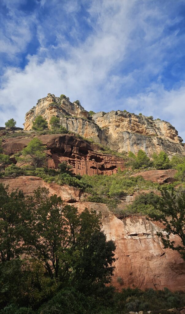 Vista panorámica de las paredes de roca de Siurana mostrando los estratos geológicos con la base de arenisca roja y la cima de caliza.
