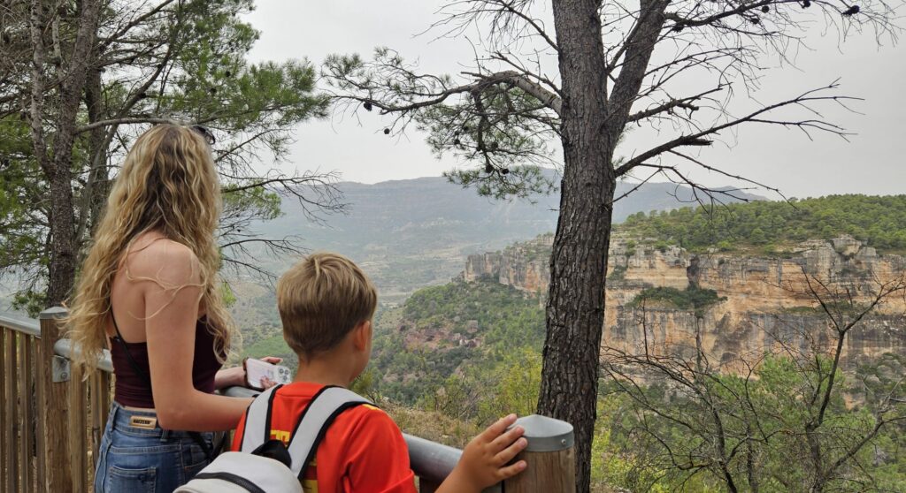 Niños disfrutando de las vistas panorámicas desde un mirador de madera hacia los acantilados y el valle de Siurana.