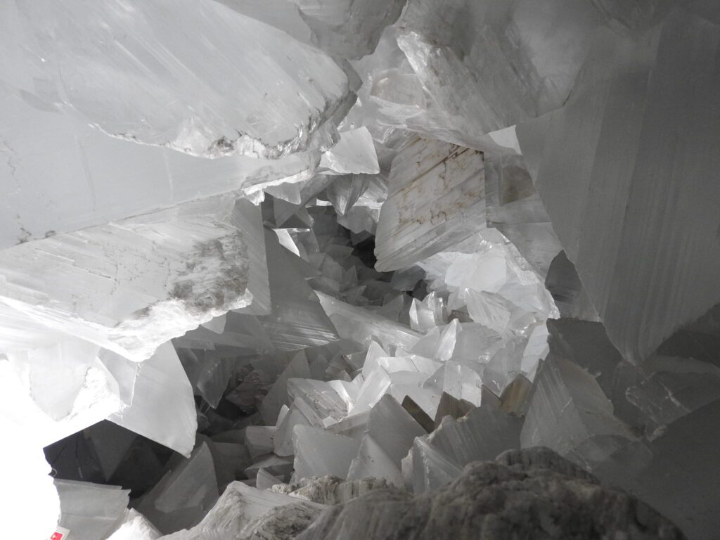 Primer plano del interior de la Geoda de Pulpí, Almería. Se observan enormes cristales de yeso transparentes y geométricos que cubren las paredes de la cavidad minera, creando una textura brillante y angular.