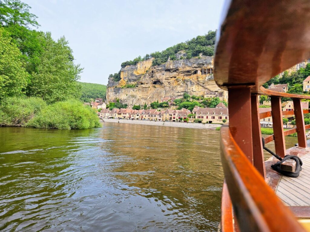 Vista desde una gabarra tradicional navegando por el río Dordoña frente al pueblo acantilado de La Roque-Gageac, Francia.