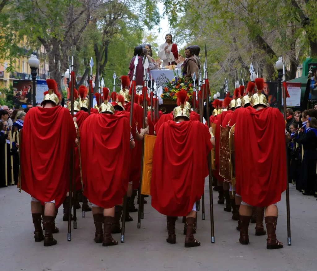 Grupo de Armats vestidos de soldados romanos con capas rojas desfilando en la procesión de Semana Santa en Tarragona.