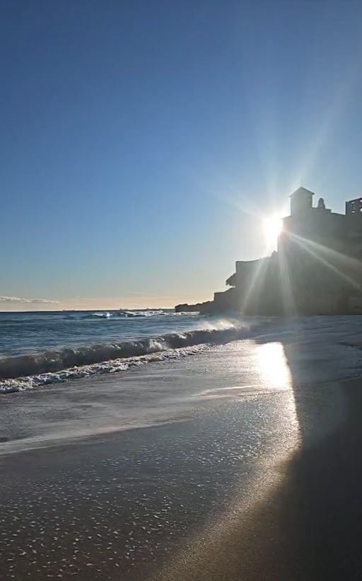 Puesta de sol en la playa de Tamarit, Tarragona, mostrando cómo la dense línea de árboles en el promontorio del castillo bloquea el horizonte abierto para el eclipse 2026.